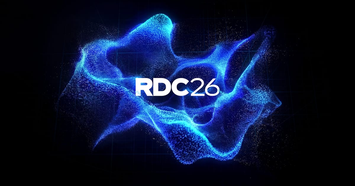 RDC26 key art with a glowing blue particle wave on a dark grid background and the white RDC26 wordmark in the center